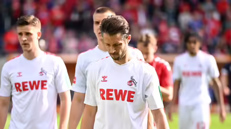 Die Kölner Spieler um Mark Uth gehen nach der Niederlage und dem Abstieg vom Rasen / © Harry Langer (dpa)