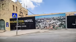 Bauzaun mit Foto und der Aufschrift "coming soon Mount Zion Hotel" in Jerusalem am 13. April 2024. / © Johannes Schidelko (KNA) Bauzaun mit Foto und der Aufschrift "coming soon Mount Zion Hotel" in Jerusalem am 13. April 2024. / © Johannes Schidelko (KNA)