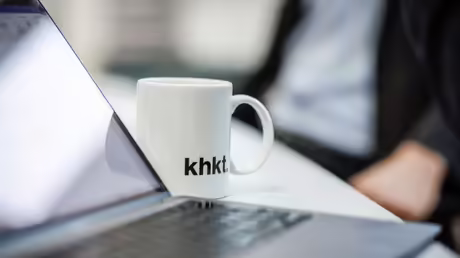 Becher mit dem Logo der KHKT neben einem aufgeklappten Laptop / © Cornelis Gollhardt (KNA) Becher mit dem Logo der KHKT neben einem aufgeklappten Laptop / © Cornelis Gollhardt (KNA)